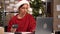 Woman wearing Santa hat working in a dropshipping office or small warehouse, preparing a parcel to deliver to the