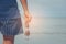 Woman wearing short pants and t-shirt standing on sand beach and holding sunglasses in hers hand.