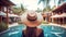 Woman wearing straw beach hat standing in front of a luxurious exotic resort pool