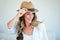 woman wearing a straw fedora smiling and looking away