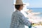 Woman wearing straw hat enjoy view from balcony of beachfront hotel or apartment