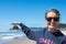 Woman wearing sunglasses pretends to touch a seastack rock in Haystack rock