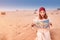 woman wearing turban reading map in Sahara desert in Africa. Travel and tourism concept