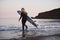 Woman Wearing Wetsuit Carrying Surfboard As She Walks Into Sea