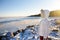 Woman wearing white jacket is walking on iced Baltic Sea coast in sunny winter day