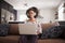 Woman Wearing Wireless Headphones Sitting On Sofa At Home Using Laptop