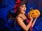 Woman wearing witch hat keeps big orange pumpkin.