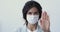 Woman wears medical mask showing stop coronavirus hand gesture