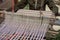 Woman weaving silk in traditional way at manual loom.