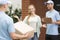 Woman welcoming professional couriers with package and receipt of delivery