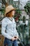 Woman in western wear in cowboy hat, jeans and cowboy boots.