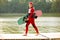Woman in wetsuit, helmet and life vest walking with a wakeboard on a pier. Sunny summer day. Safety in sport. Water sport