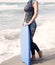 Woman in wetsuit and swimming board standing by the ocean