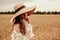 Woman wheat field nature. Happy young woman in sun hat in summer wheat field at sunset. Copy space, sunset, flare light