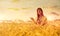 Woman in wheat field at sunset