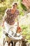 Woman With Wheelbarrow Working Outdoors In Garden