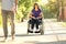 Woman in wheelchair looking at healthy person outdoors