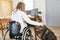 Woman in a wheelchair at the PC in the home office with assistance dog