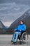 A woman in a wheelchair on a point view admires the high mountains. Thrust to life.