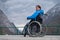 A woman in a wheelchair on a point view admires the high mountains. Thrust to life.
