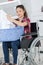 Woman on wheelchair putting clothes into washing machine