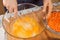 Woman whisks chicken eggs lying in a glass bowl with a kitchen whisk.