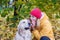 Woman whispers something in her retriever`s ear in an autumn park among yellow leaves