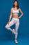 Woman in white activewear posing before workout on blue background