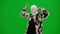 Woman in white balaclava, fur coat and dress walking and dancing merrily with her hands up. Woman freak on green