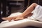 Woman in white bathrobe lying on deckchair with bent knee