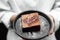 Woman in white cloth hand holding homemade chocolate cake with heart topping