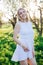 woman in white dress in a blossoming garden in a park in nature journey walk