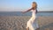 Woman in white dress dancing on the beach