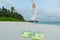 Woman in a white dress dancing on the tropical beach against flip flops closeup