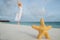 Woman in a white dress dancing on the tropical beach against starfish closeupops closeup