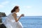 Woman in white dress drinking coffee contemplating on the beach