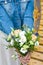 Woman in white dress and jean jacket with bouquet of flowers