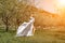 Woman white dress park. A woman in a white dress runs through a blossoming cherry orchard. The long dress flies to the