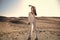 Woman in white dress in sand dunes.