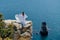 Woman in a white dress on the sea. Side view Young beautiful sensual woman in white long dress posing on a rock high