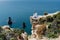 Woman in a white dress on the sea. Side view Young beautiful sensual woman in white long dress posing on a rock high