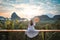 Woman with the white dress sit and see the mountain in early morning at Samet Nangshe viewpoint in Andaman sea on morning cloudy