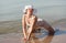 Woman in white hat posing against the sea