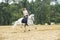 Woman on white horseback on stubblefield