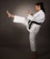 Woman in white kimono kicks high in the air - a karate martial art girl