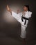 Woman in white kimono kicks high in the air - a karate martial art girl