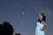 Woman in white long dress under starry night. Woman looking to starry night. Woman under night sky,