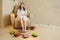 Woman in a white robe sitting in a armchair and relaxing her feet in a silver spa bowl with water surrounded by flowers