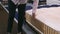 A woman in a white shirt examines the mattress, she squats and and sits down at the mattress