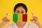 A woman in white shirt with Mali flag on hygienic mask in her hand and lifted up the front face on yellow background. Tiny
